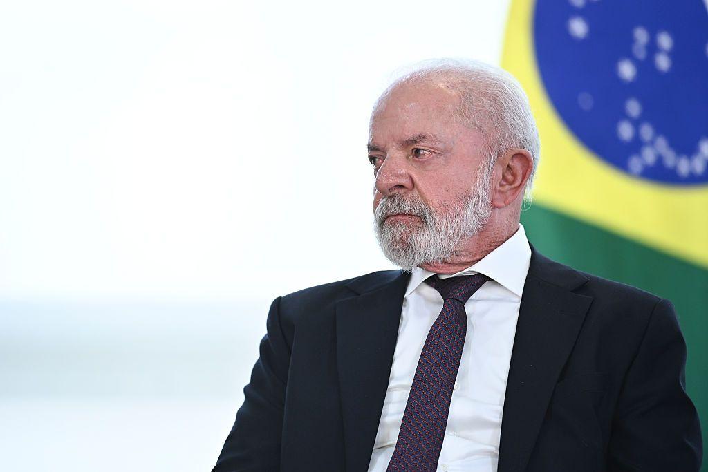 O presidente brasileiro Lula, de terno e gravata, com fundo que cont&eacute;m bandeira do Brasil