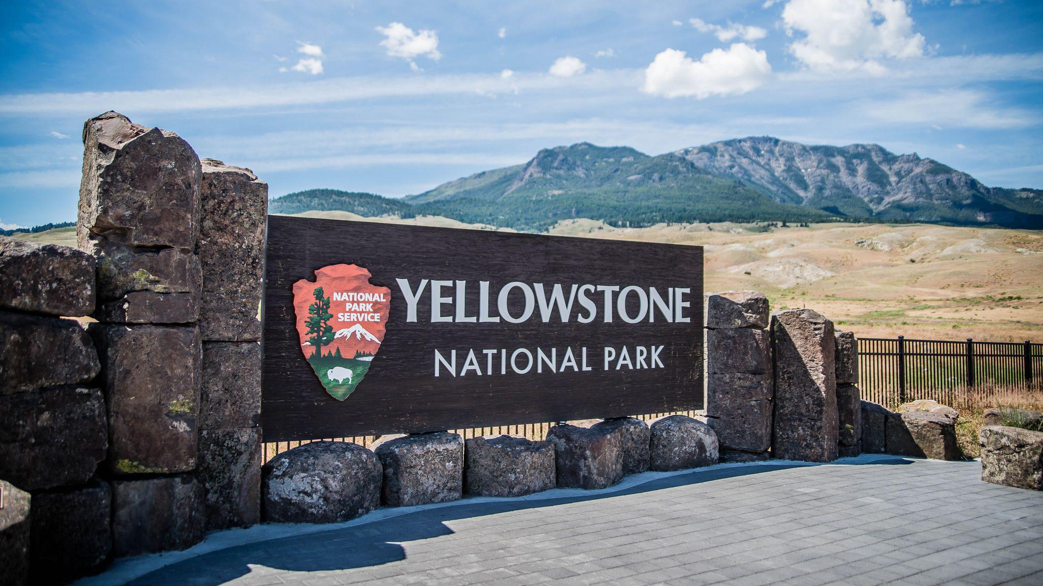 Placa de identifica&ccedil;&atilde;o do Parque Nacional de Yellowstone, nos Estados Unidos, com deserto e montanha ao fundo