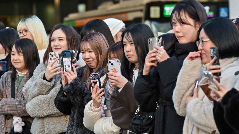 一群日本女性舉起手機記錄和拍攝眼前的場景