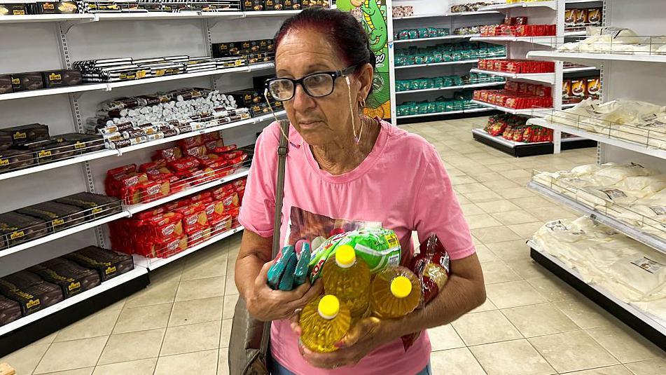 Mujer sostiene varios productos en un supermercado estatal dolarizado en un barrio de La Habana. 