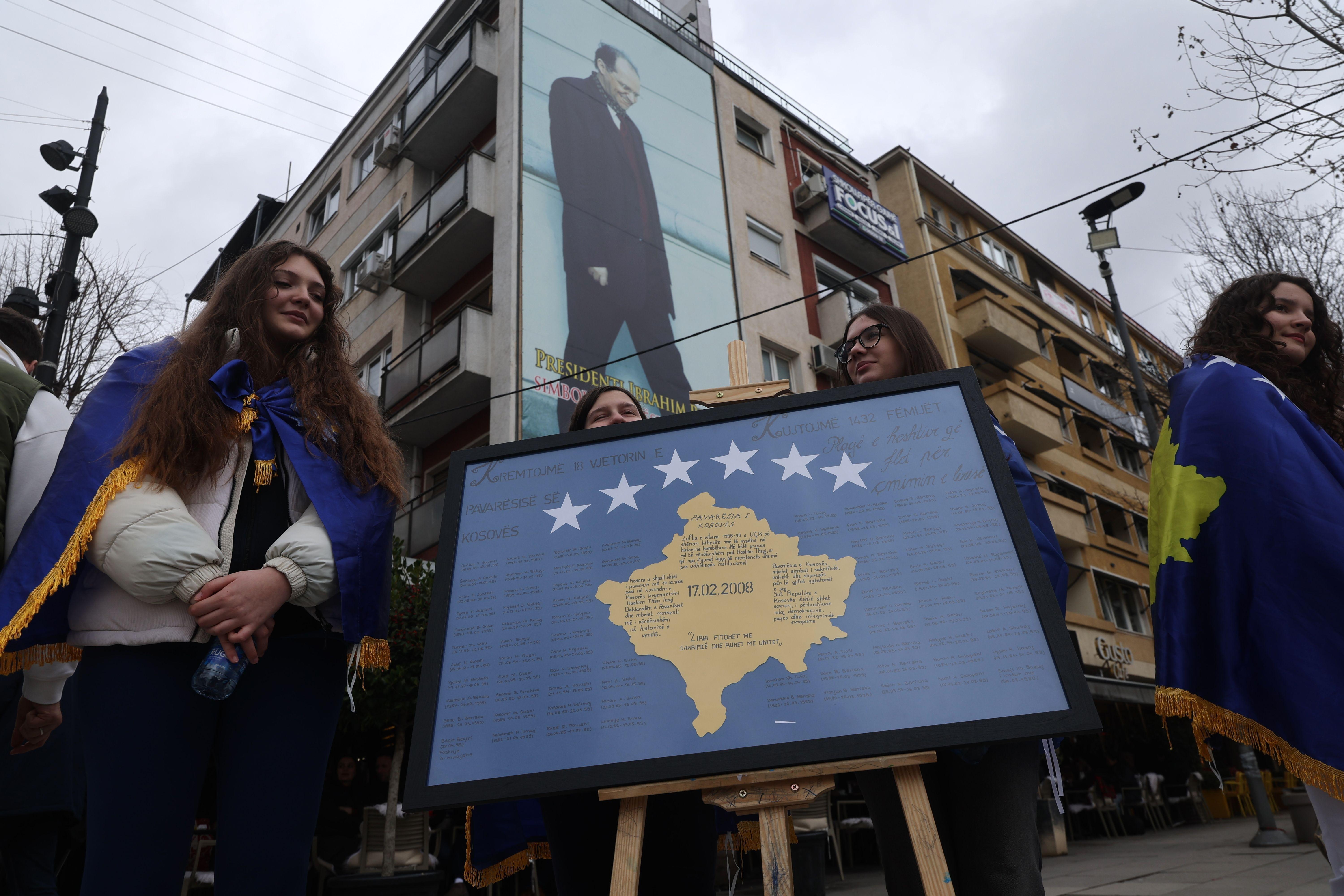 Devojke ogrnute kosovskim zastavama stoje pored panela sa imenima žrtava srpskog režima tokom proslave 18. godišnjice nezavisnosti zemlje u Prištini, Kosovo, 17. februara 2026. 