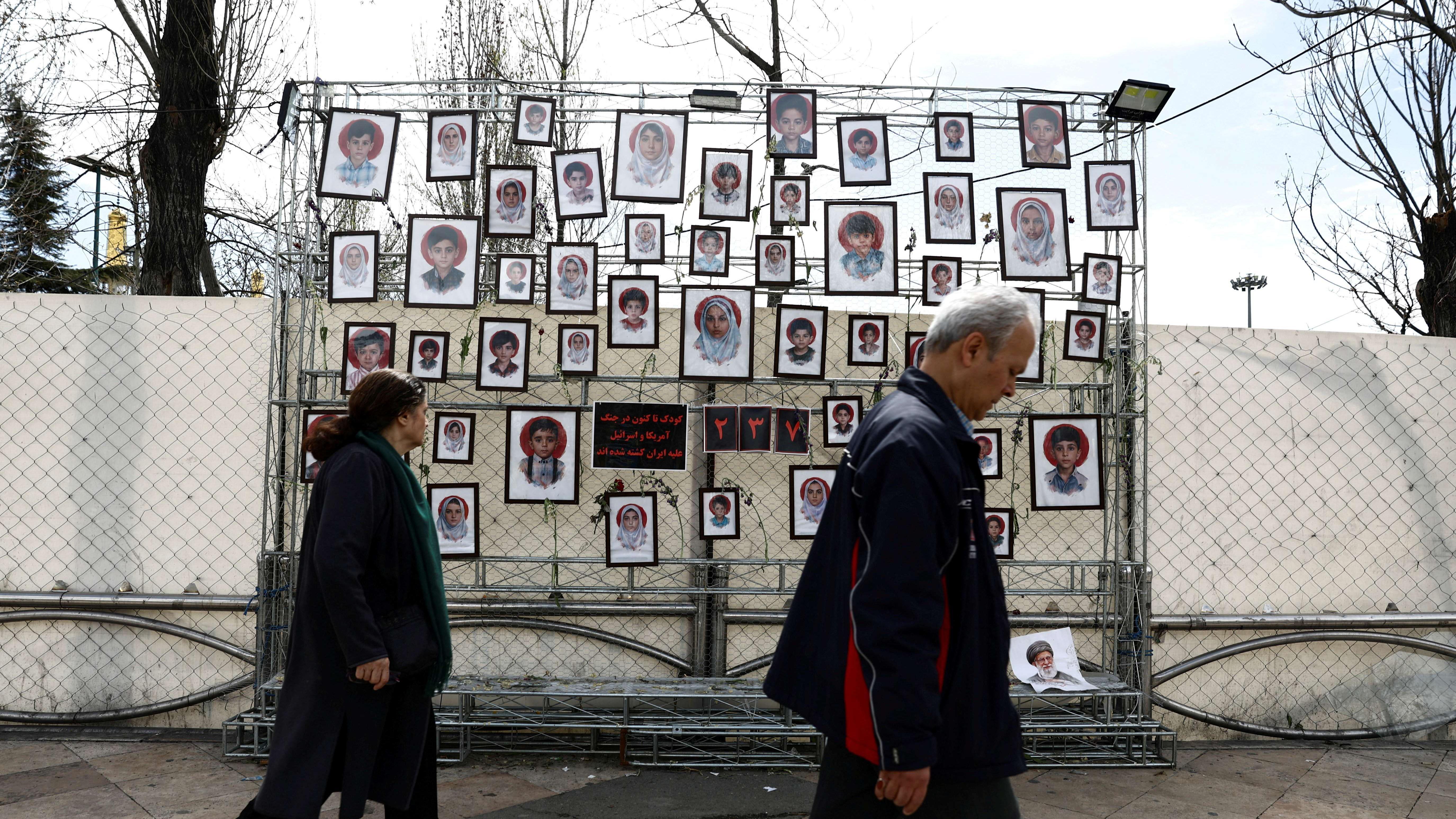 Ljudi hodaju pored table sa slikama poginule dece u Teheranu