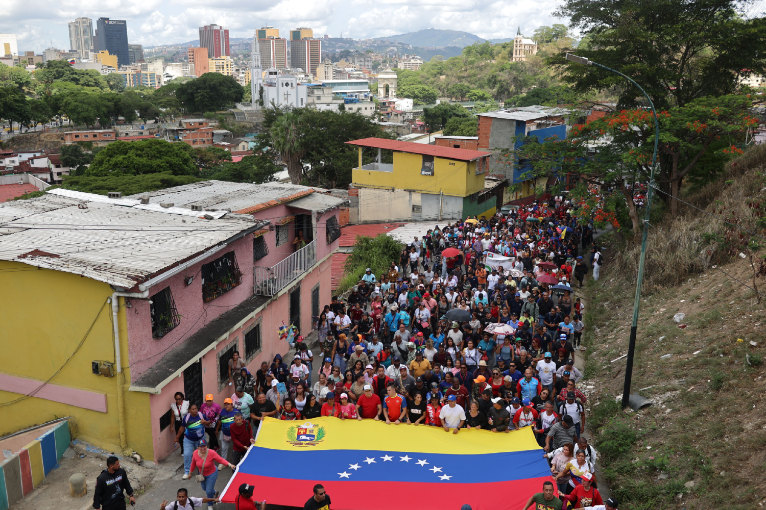 Partidarios del chavismo marchan con una gran bandera de Venezuela por un sector popular de Caracas.