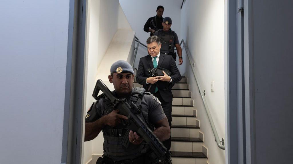 Lincoln Gakiya e policiais da sua escolta descendo uma escada. 