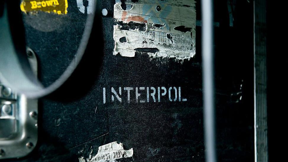 Interpol escrito en letras blancas sobre un panel negro.