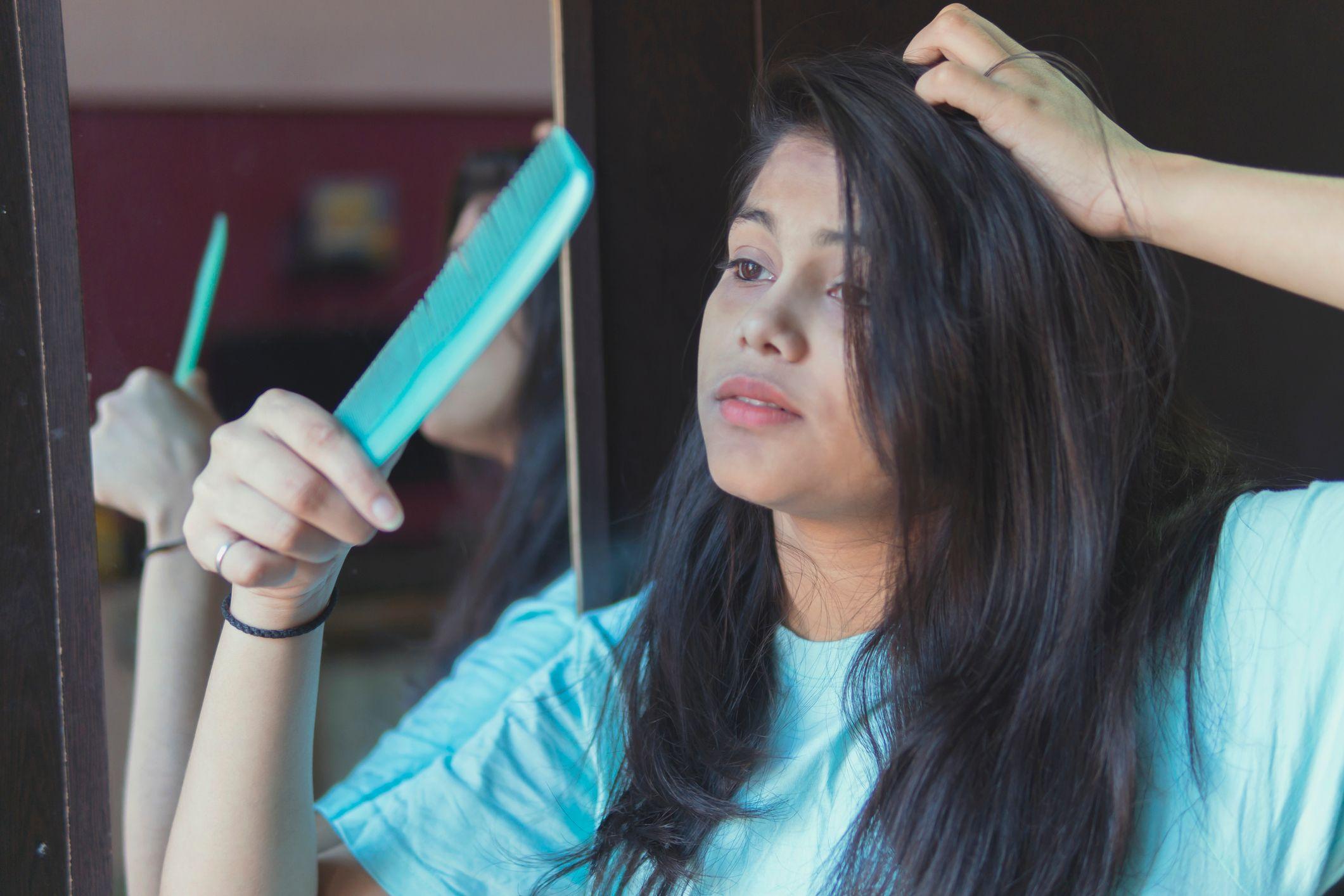 Indian young Frustrated girl holds comb with her hair fell out. indoor shoot at home.