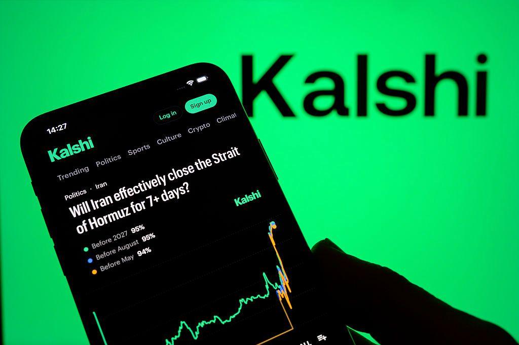 Con el fondo verde y la palabra Kalshi en negro, se ve en primer plano un teléfono sostendio por una mano en el que está abierto el app de Kalshi, con categorías arriba, la pregunta, información sobre el porcentaje adivinado de probabilidad, y un gráfico. 