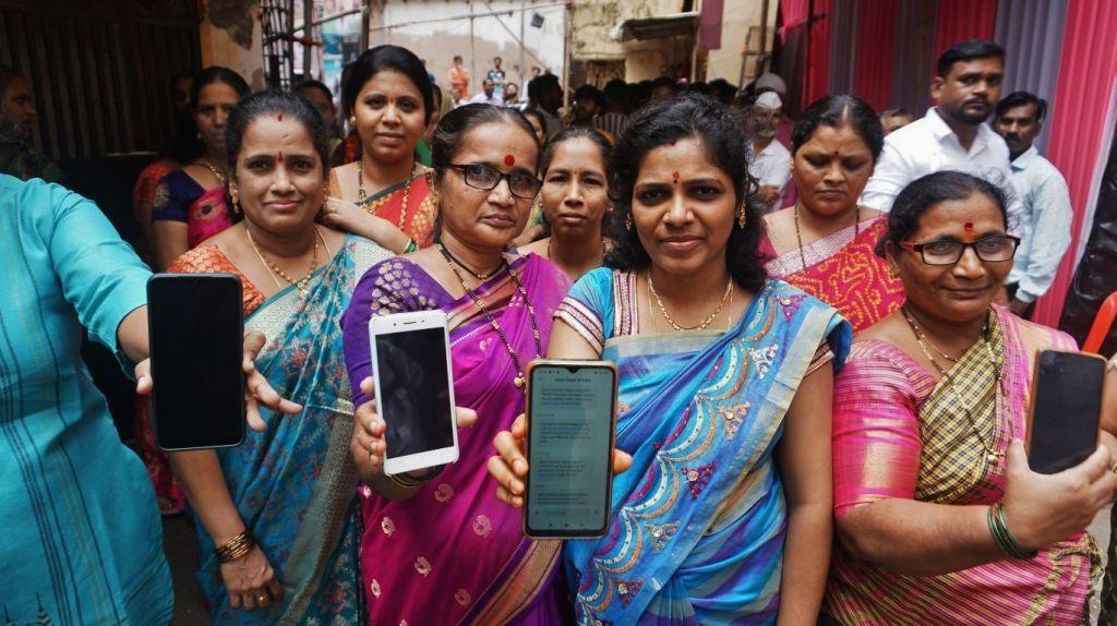Mujeres beneficiarias del programa Mukhyamantri Ladaki Bahin Yojana muestran sus libretas bancarias y el mensaje de confirmación de la recepción del dinero del programa en sus teléfonos móviles en Kisan Nagar, Thane, India.