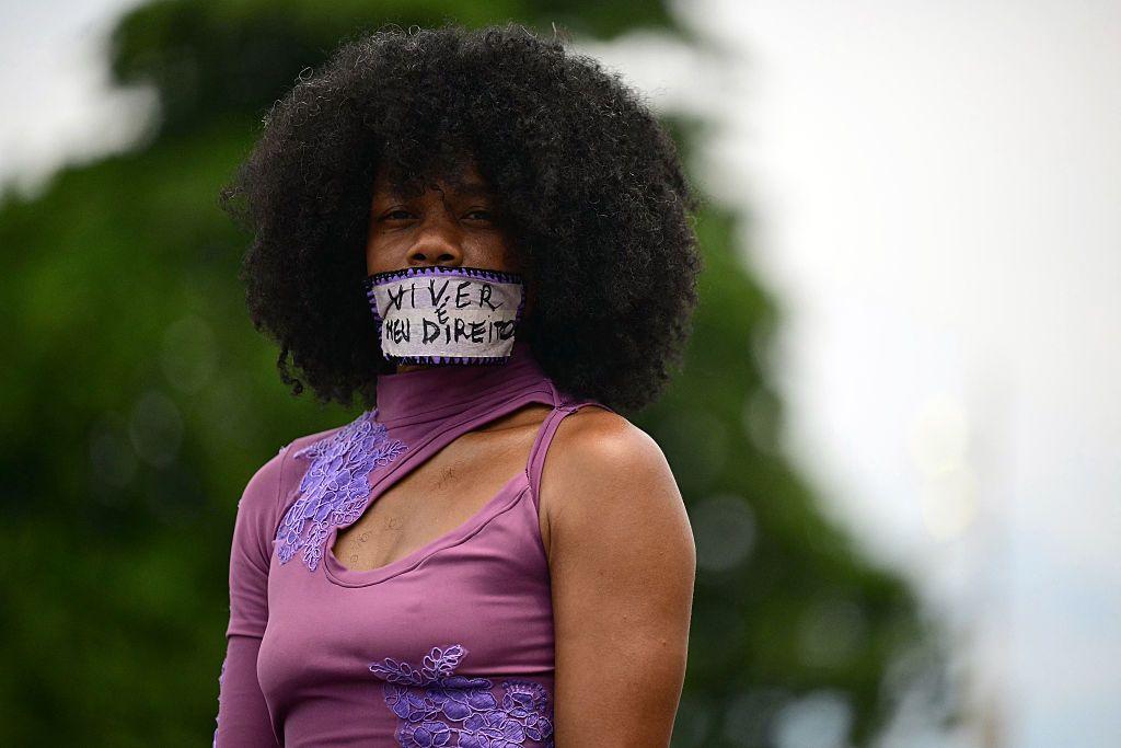 Una mujer con la boca cubierta por un cartel en el que se lee "vivir es mi derecho".