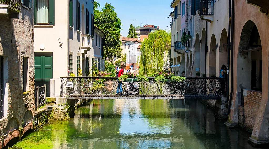 Mulher caminha em ponte sobre canal em Treviso