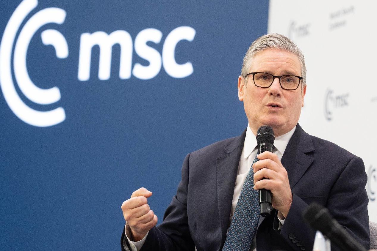 Keir Starmer veste um terno escuro, gravata azul e est&aacute; segurando um microfone com sua m&atilde;o esquerda na Confer&ecirc;ncia de Seguran&ccedil;a de Munique