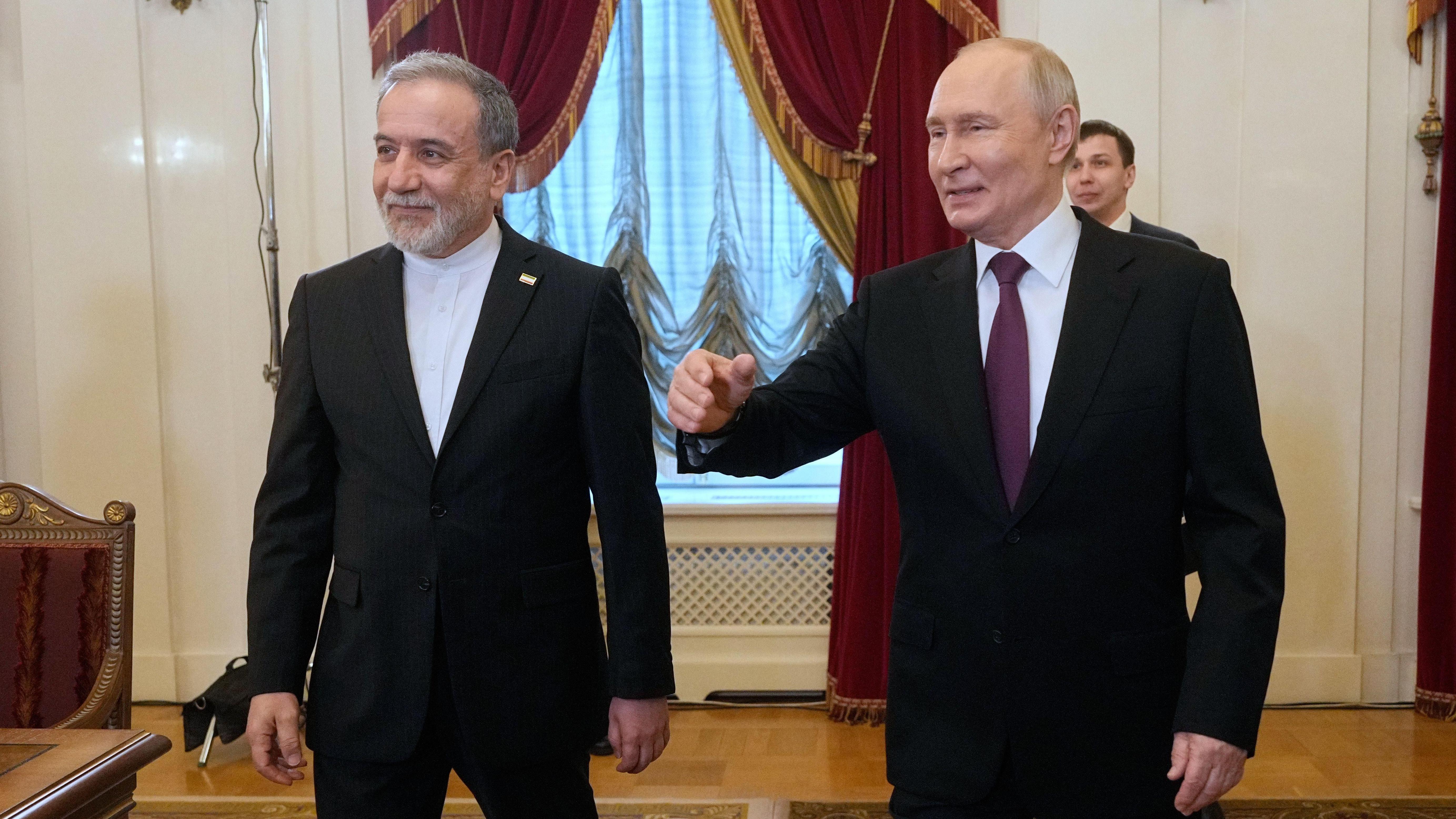 Abbas Aragachi (izq.) y Vladimir Putin fotografiados juntos en San Petersburgo. Ambos visten trajes oscuros y están de pie en un salón con cortinas ornamentadas