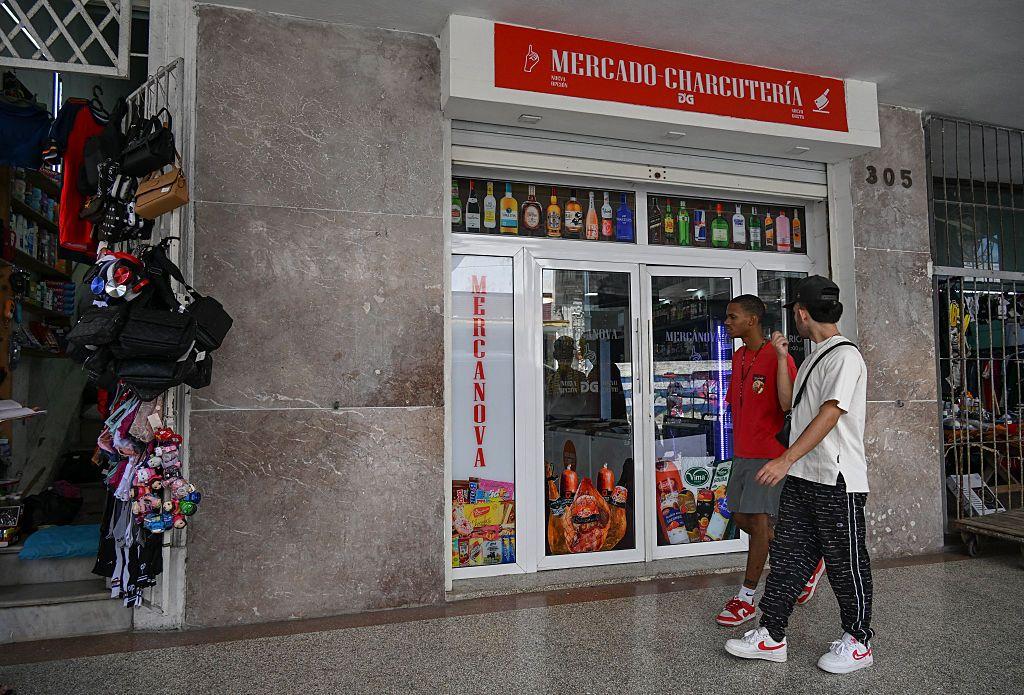 Cubanos pasan frente a comercio.