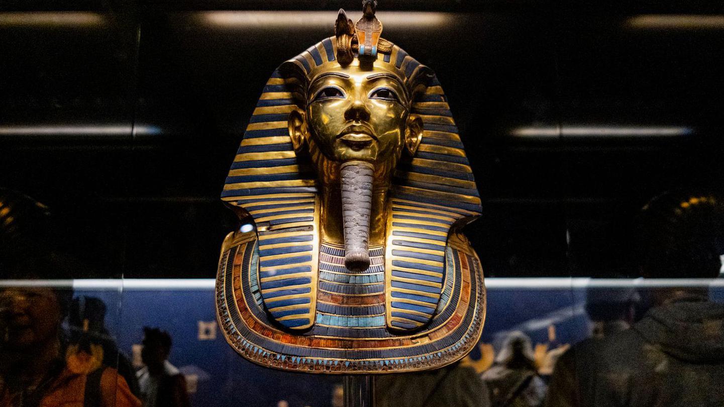 Los visitantes pasan junto a la máscara funeraria de oro y turquesa de Tutankamón expuesta en el Museo Egipcio de El Cairo, el 2 de diciembre de 2024.