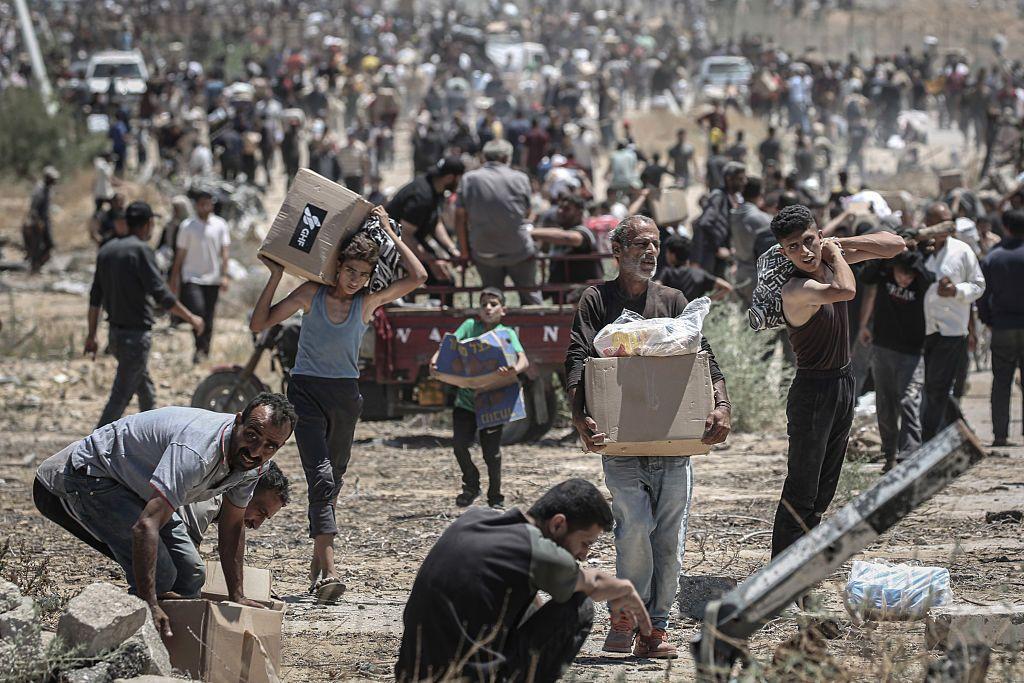 Palestinos con cajas en un centro de distribución de ayuda humanitaria en Gaza.