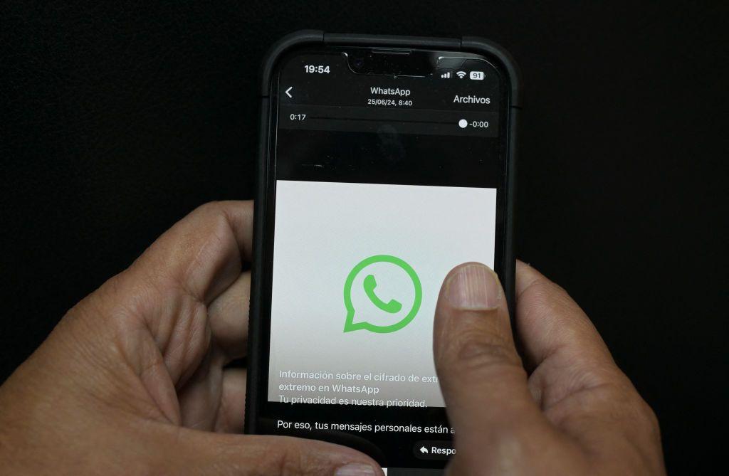 Una persona sostiene su teléfono y se ve el logo de WhatsApp.
