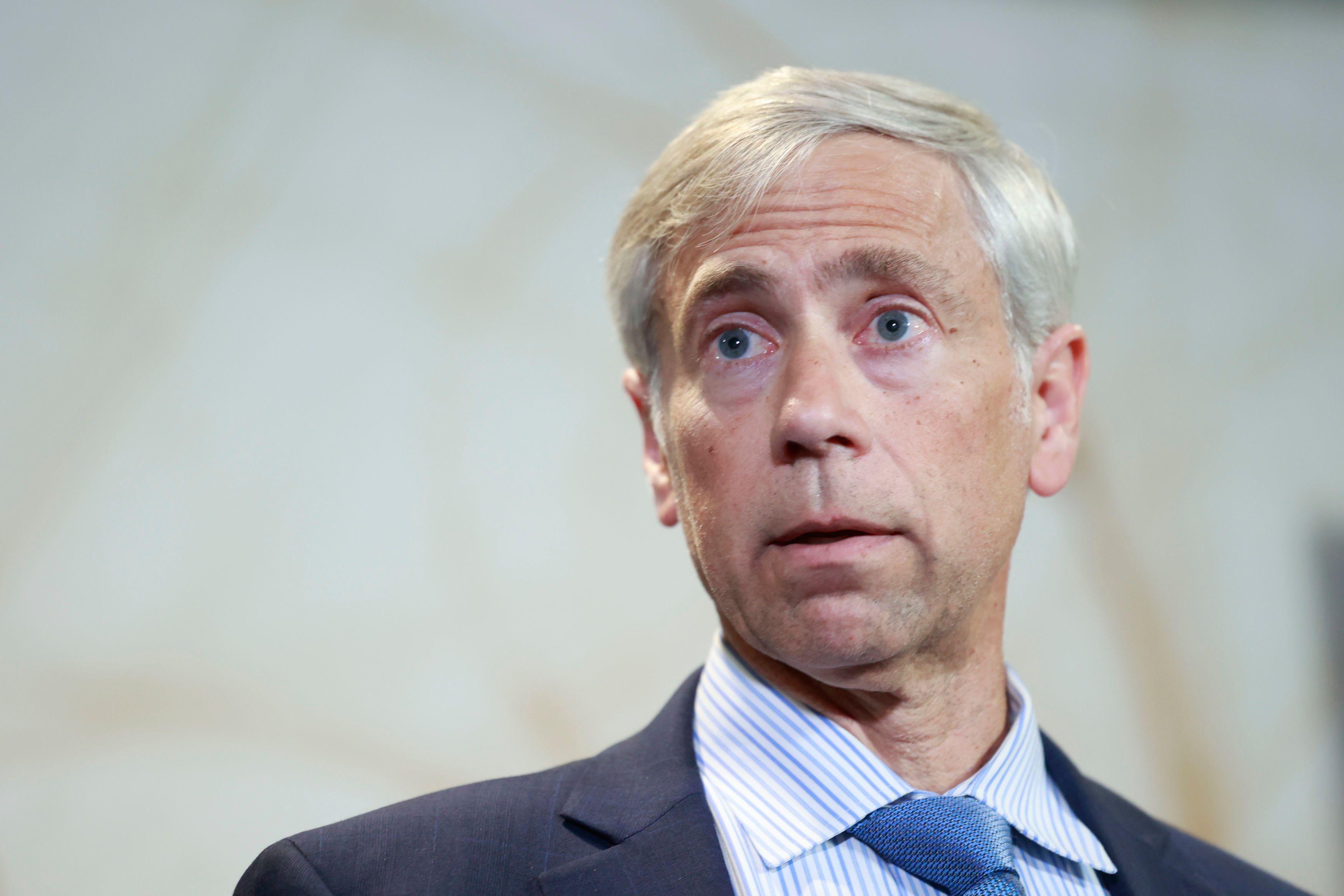 巴里・波拉克身穿海軍藍色西裝外套，搭配藍白條紋襯衫，以及一條帶有細小圓點的藍色領帶