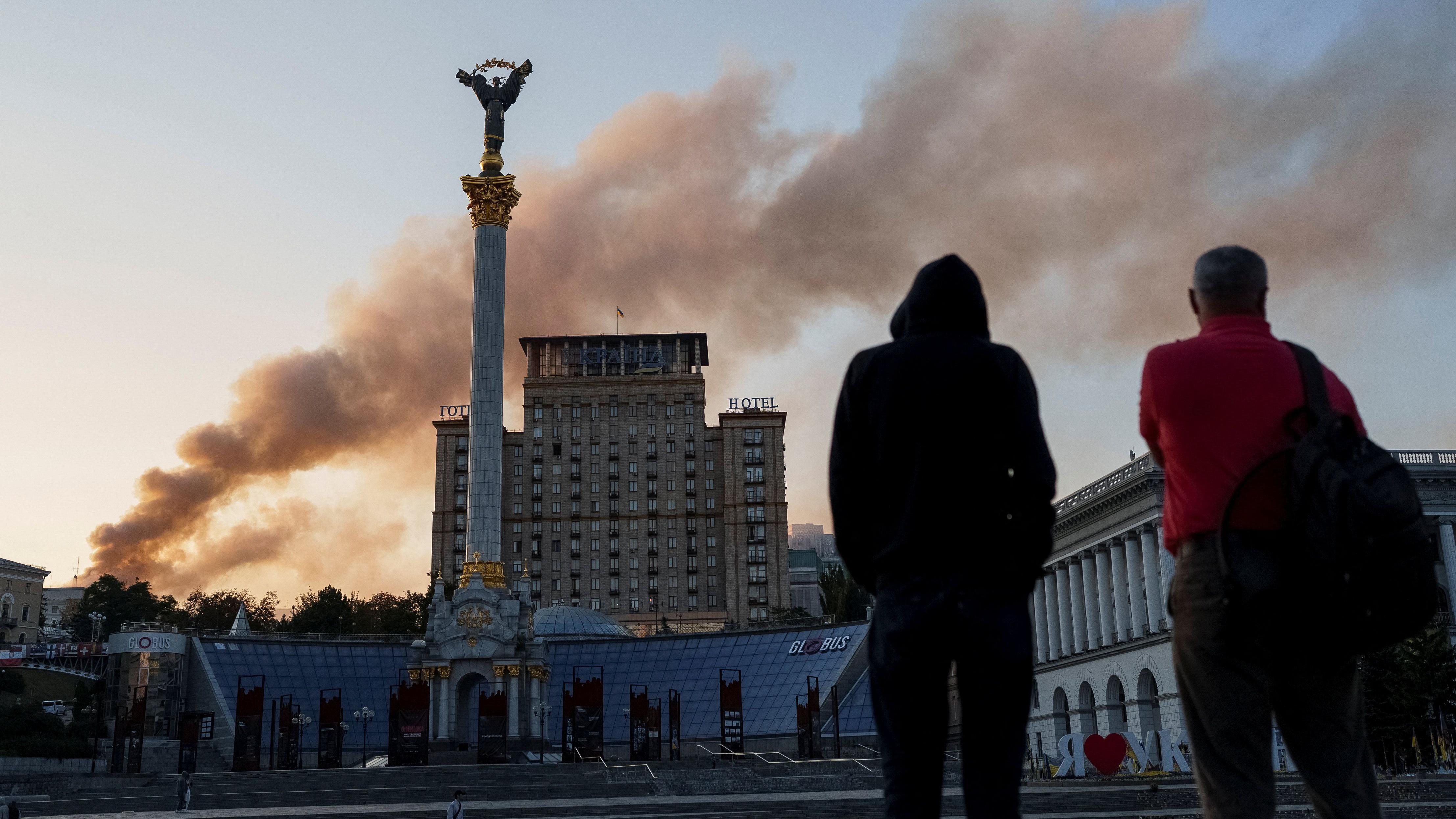 Unos hombres ven la columna de humo que sale del edificio del Gabinete.