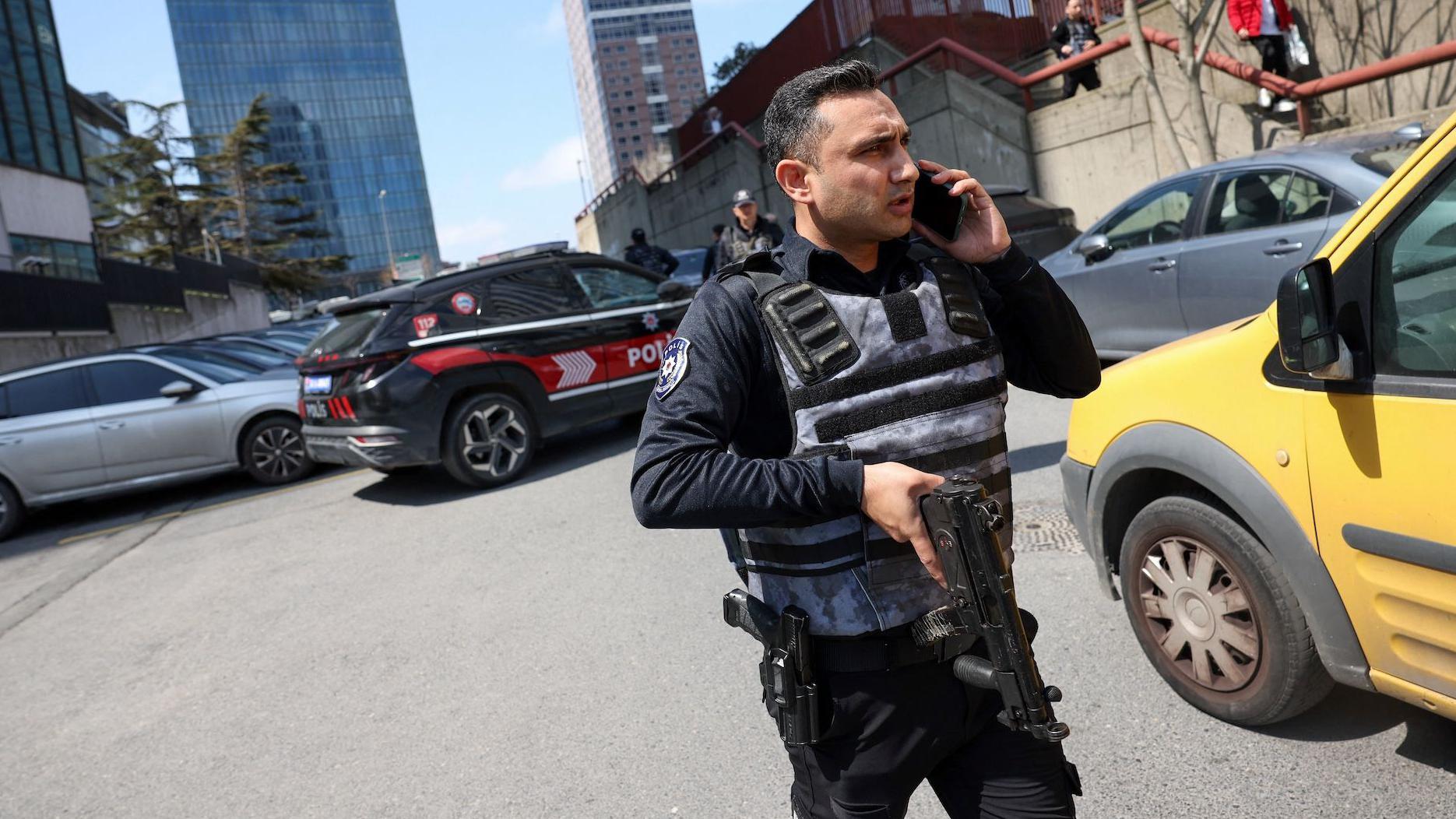 Policajac sa automatskom puškom ispred automobila