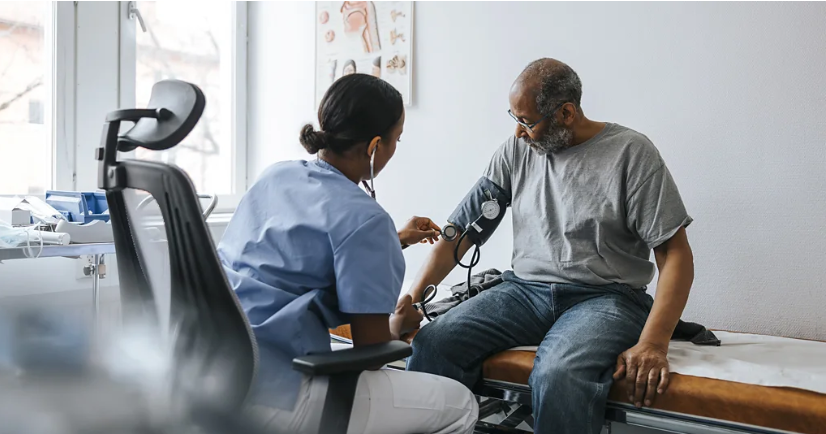 رجل يجلس في مركز طبي وتجلس أمامه ممرضة تقيس له ضغط الدم.