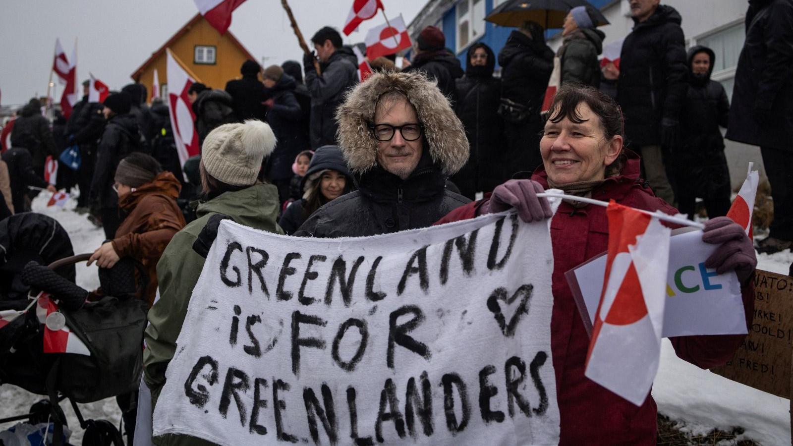 Homem e mulher seguram um cartaz com os dizeres: 'A Groenl&acirc;ndia &eacute; para os groenlandeses' durante protesto em Nuuk