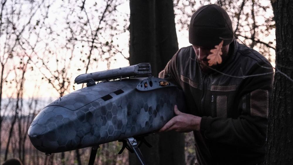 Pilot u vojničkoj uniformi sklapa bombarderski dron u šumi