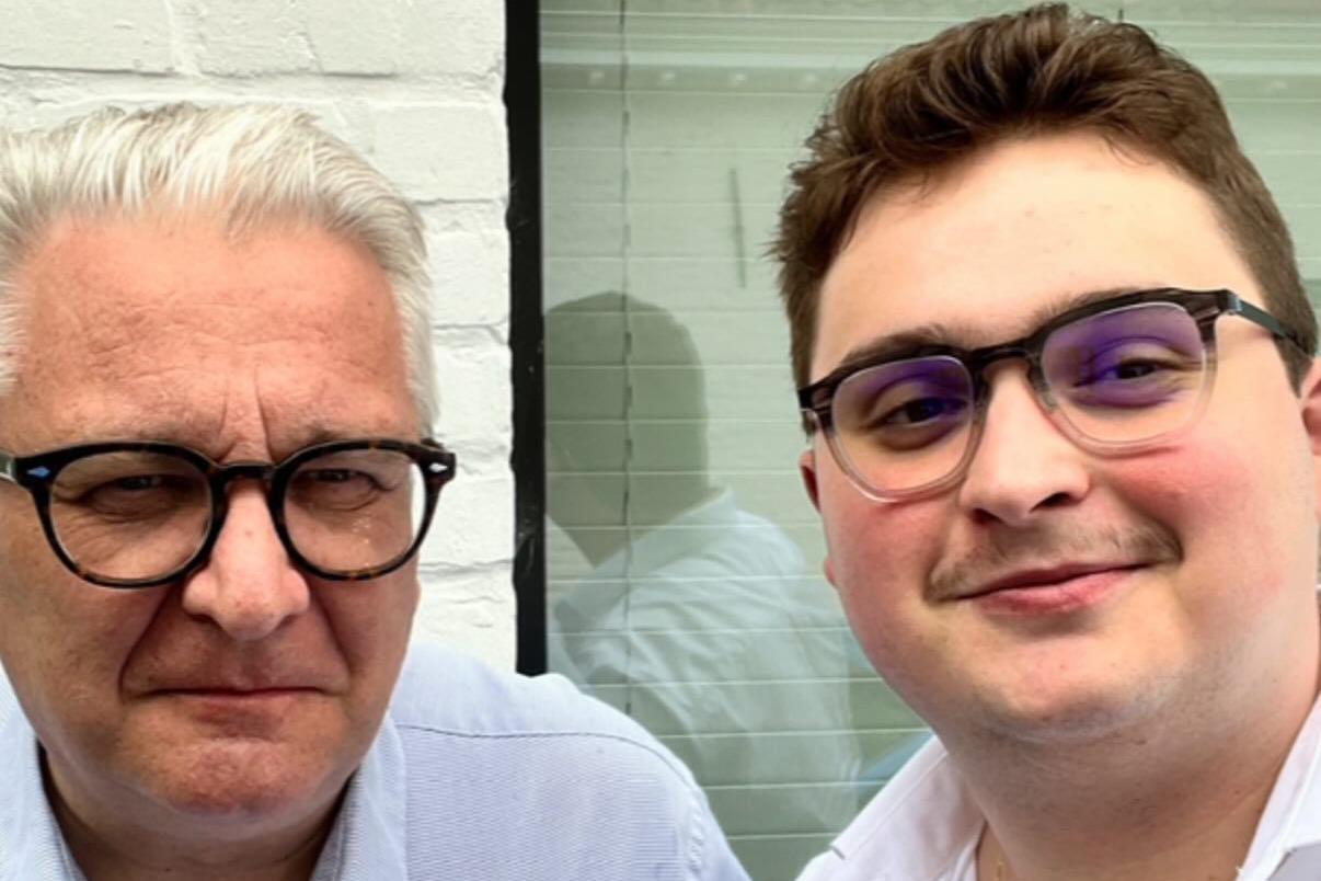 A close-up of two men both wearing glasses 