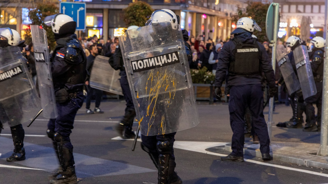 Policajac u opremi za razbijanje demonstracija drži štit na kojem je razbijeno jaje