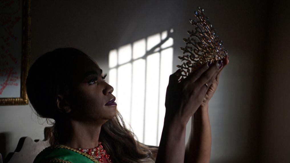 Mujer mira una corona de un concurso de belleza