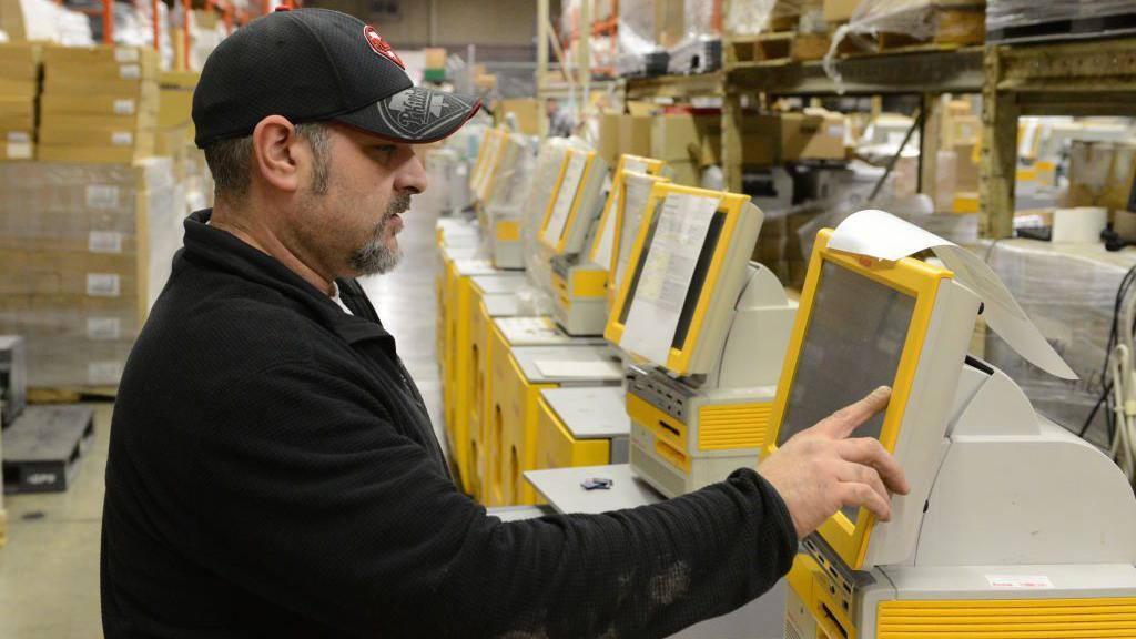 Un técnico realiza una verificación en un quiosco de impresión de fotografías Kodak.