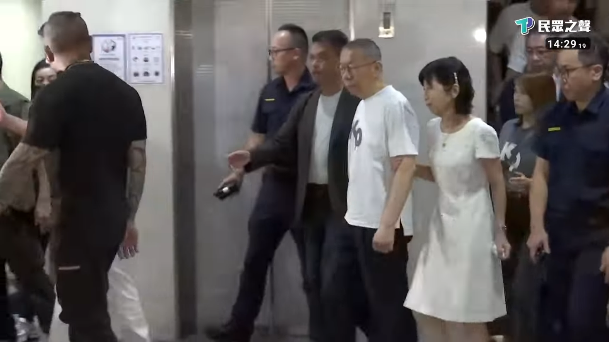 柯文哲身穿印有「KP」字樣的白色T恤步出台北地方法院，其妻子陳佩琪陪同在側。