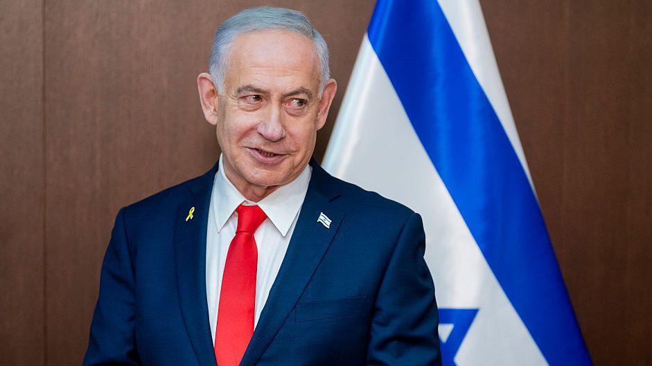 El primer ministro israelí, Benjamín Netanyahu, con una bandera israelí tras él.