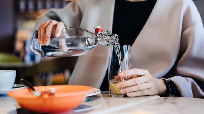 Mulher servindo &aacute;gua em um copo em um restaurante