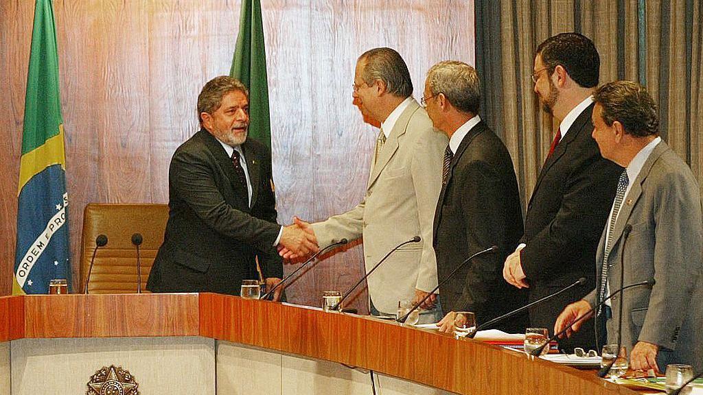 Lula e Jos&eacute; Dirceu apertam as m&atilde;os, de p&eacute;, em um gabinete. 