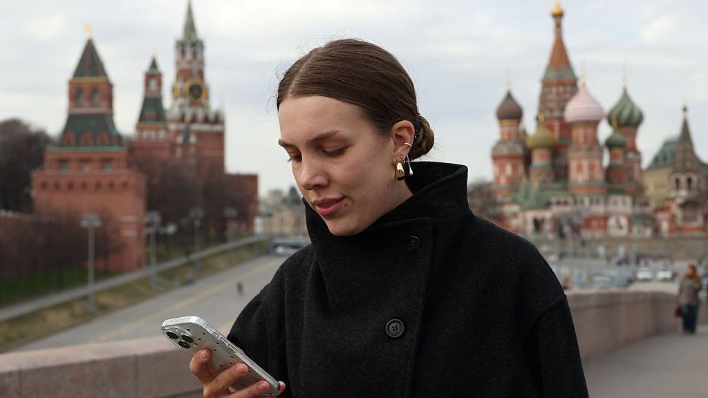 Una mujer usa su teléfono cerca del Kremlin.