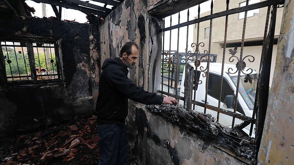Un hombre entre los escombros de una casa incendiada