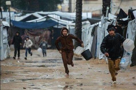 صبيان يسعيان للحصول على مياه شرب بين الخيام 