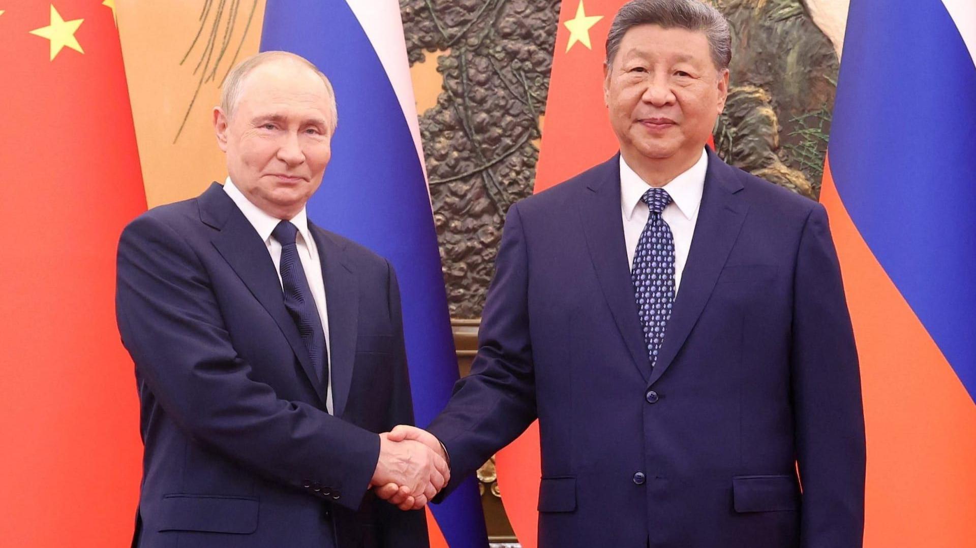 الرئيسان الروسي بوتين والصيني شين بينغ يتصافحان أمام أعلام البلدين