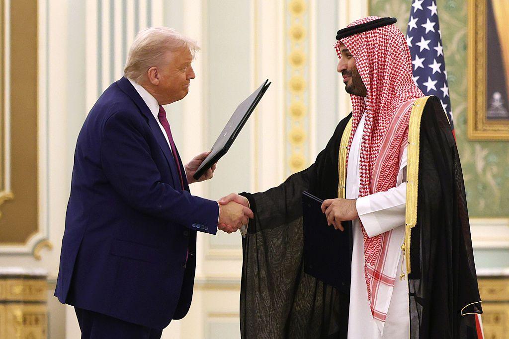 El príncipe Mohammed bin Salman saluda a Donald Trump, que sostiene una carpeta en su otra mano