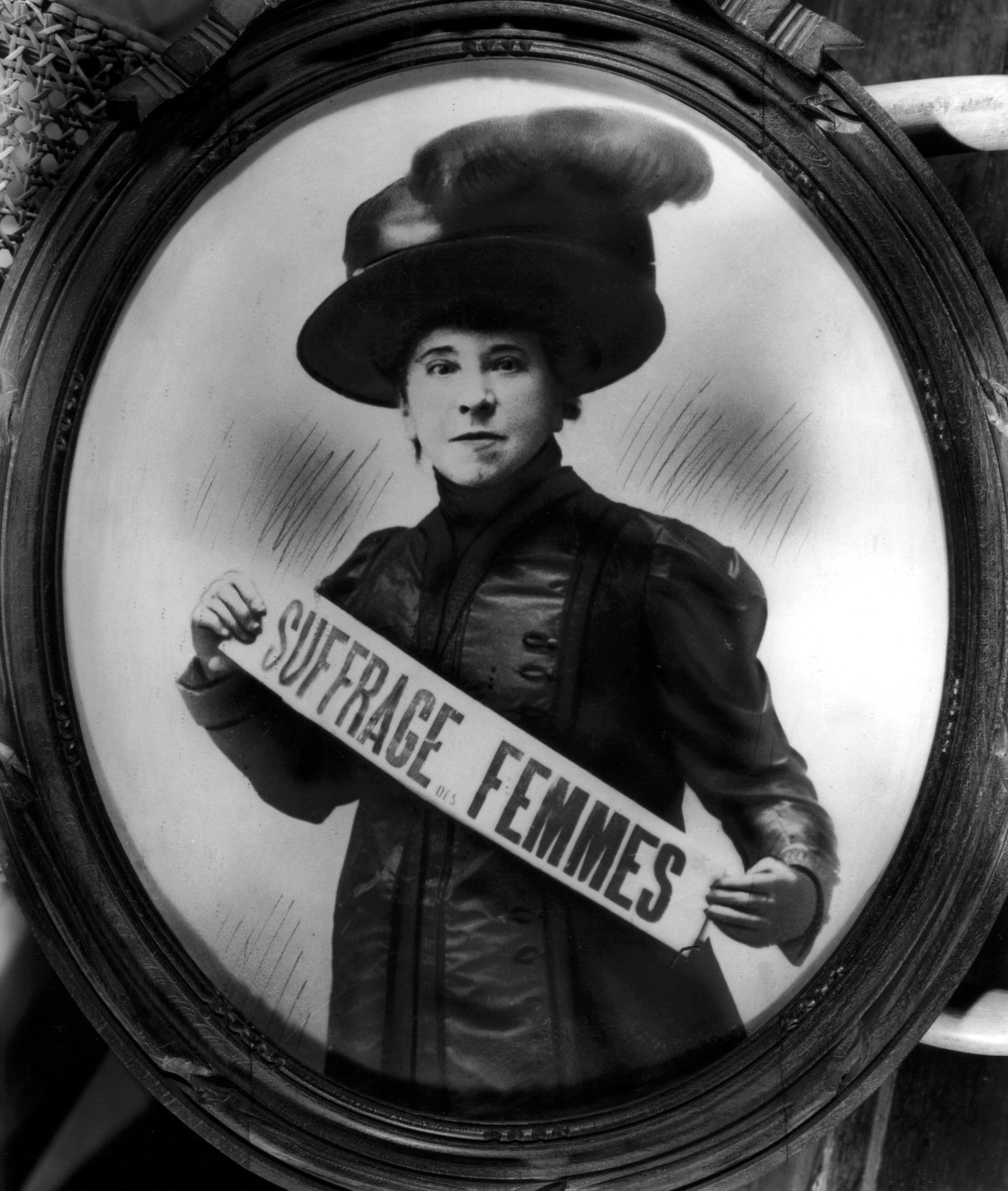 Foto retrato de Hubertine Auclert (1848-1914), una de las pioneras del movimiento sufragista en Francia, sosteniendo en las manos un banda donde se lee: "suffrage femmes".
