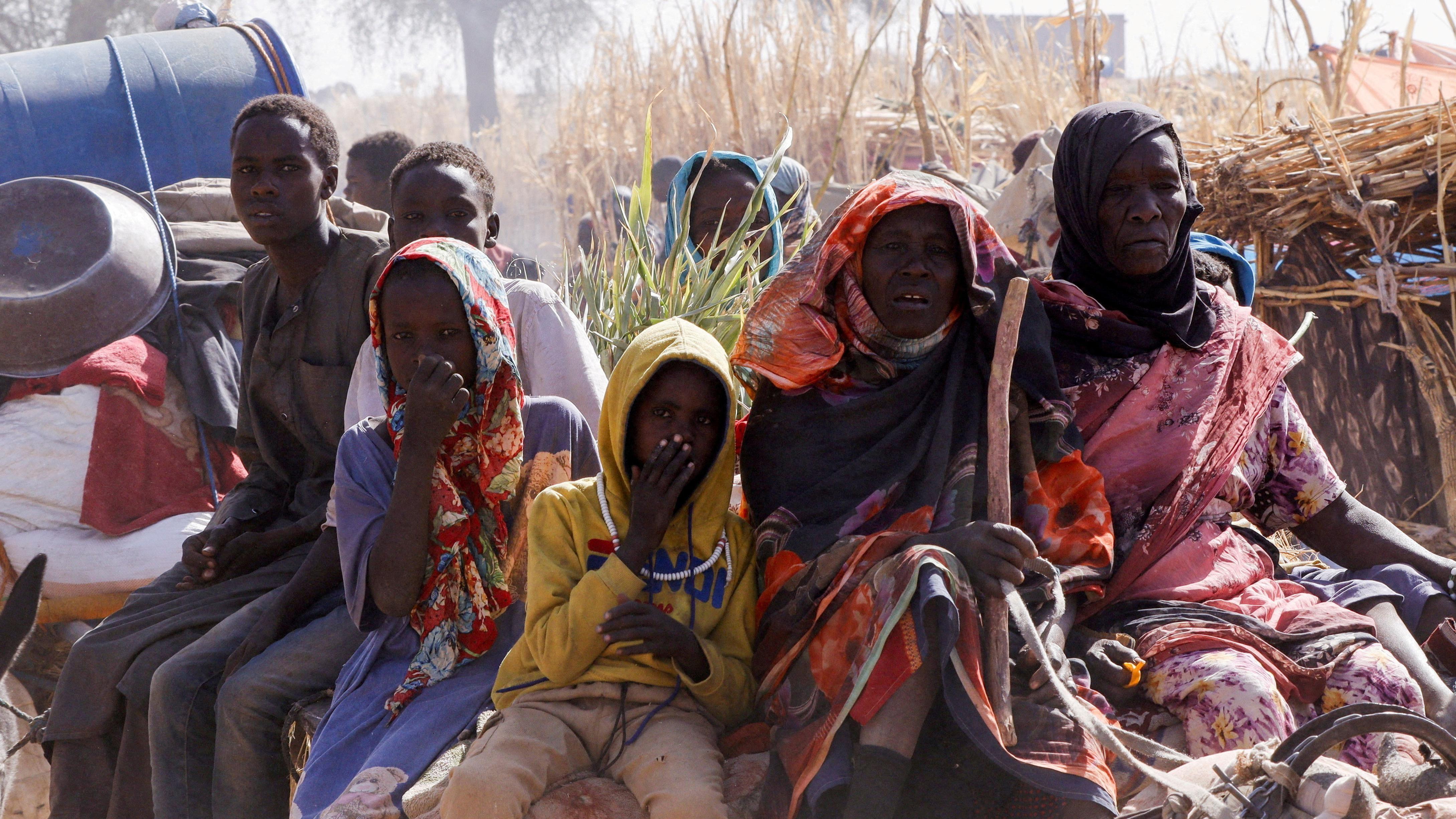 سيدات ورجال وأطفال يجلسون في الجزء الخلفي من سيارة كارو تقل نازحين بسبب القتال في السودان.