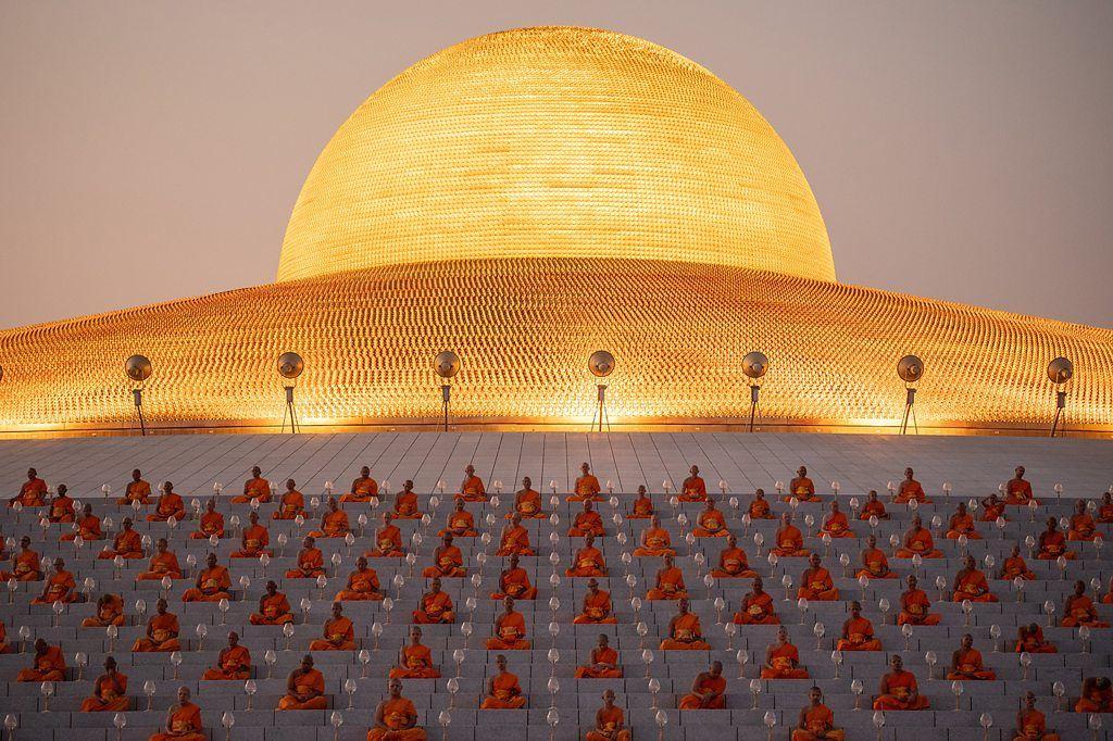 Monges rezando em frente à cúpula dourada do templo Wat Phra Dhammakaya, na Tailândia