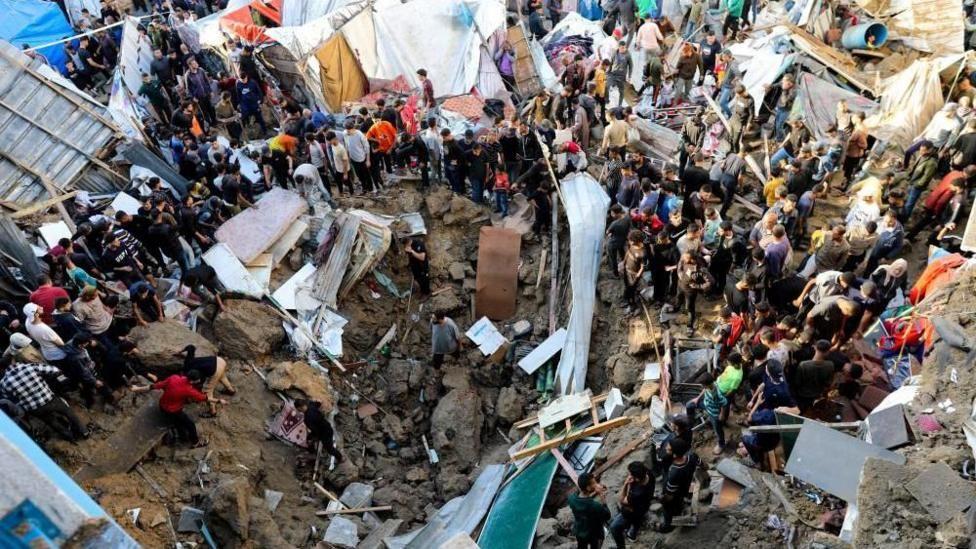 Personas en Gaza en torno a escombros tras bombardeos israelíes