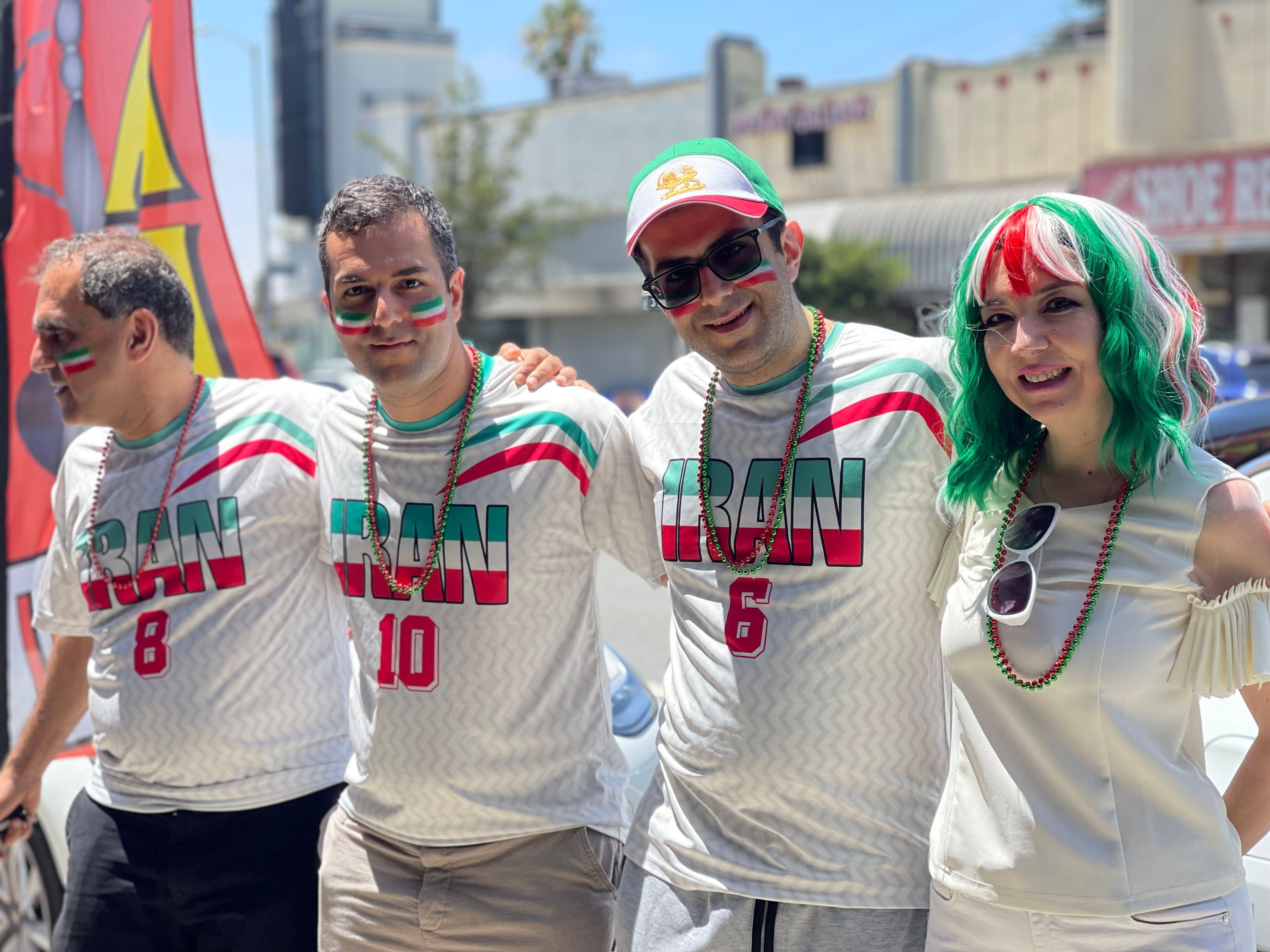 Parsa Tafreshi (segundo desde la izquierda) y tres miembros de su familia vestidos con camisetas blancas en las que se lee "Irán" y pintura tricolor en la cara, posan abrazados y mirando a cámara en "Teherángeles", Los Ángeles, Estados Unidos, el 15 de junio de 2026. (Foto: Leire Ventas)
