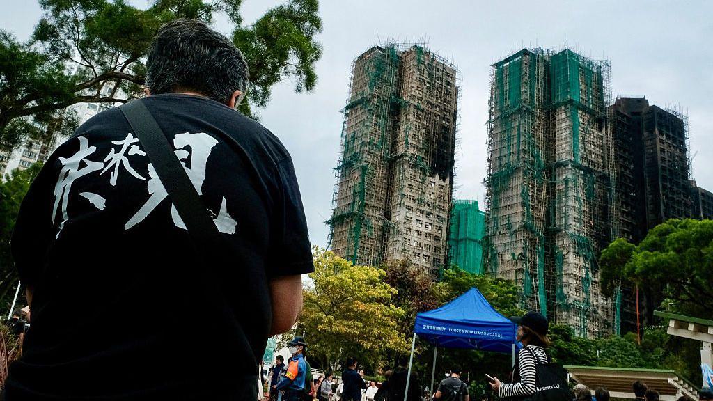 Relatives of firefighter Ho Wai-ho, who died in the deadly fire at the Wang Fuk Court residential estate in Tai Po district, hold his portrait during his burial at Gallant Garden in Hong Kong on December 19, 2025. 