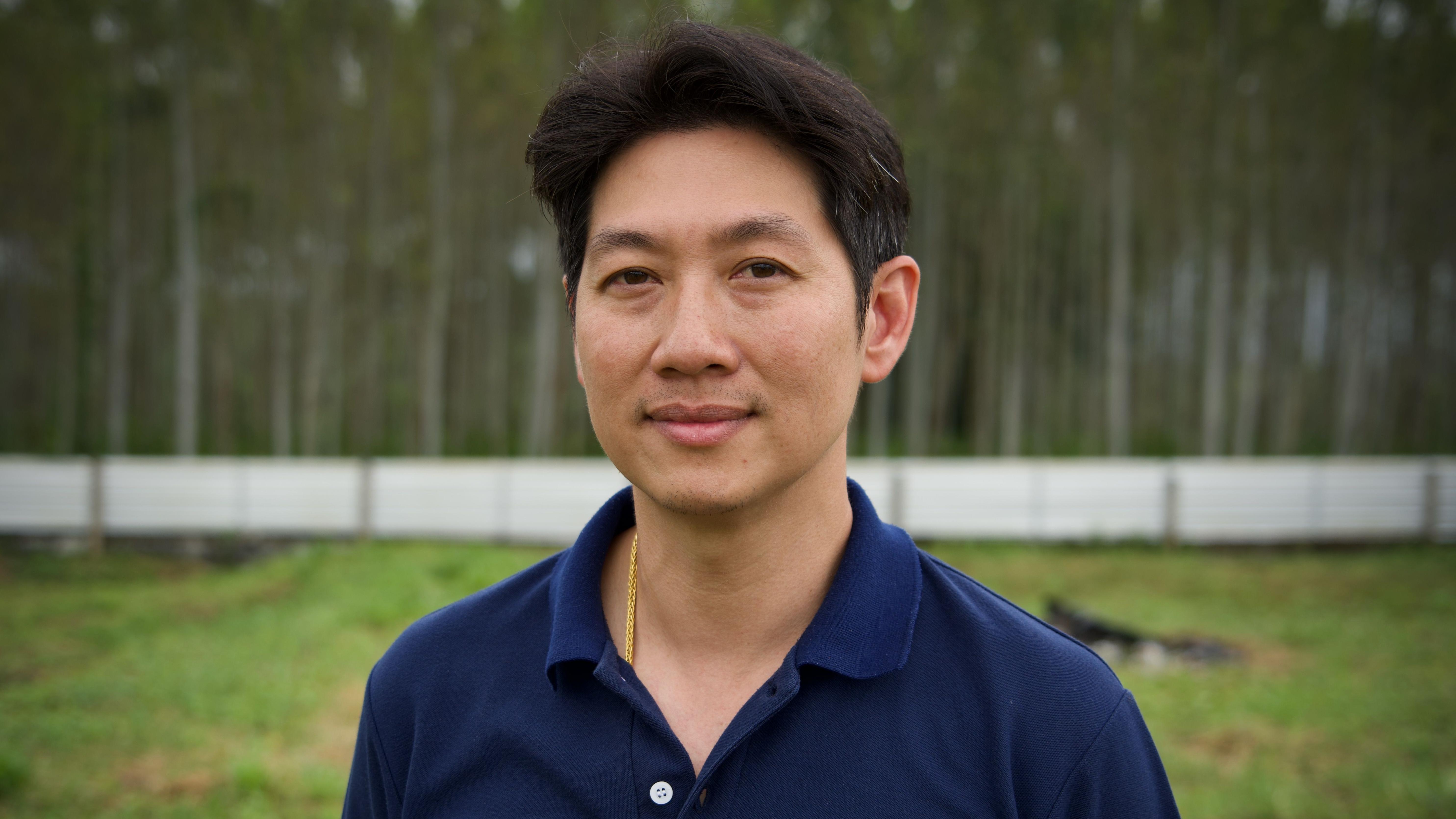 沃拉武·西里蓬身穿海軍藍襯衫，站在他的農場上