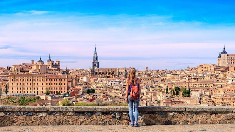 Jovem de costas, olhando para uma cidade ao fundo
