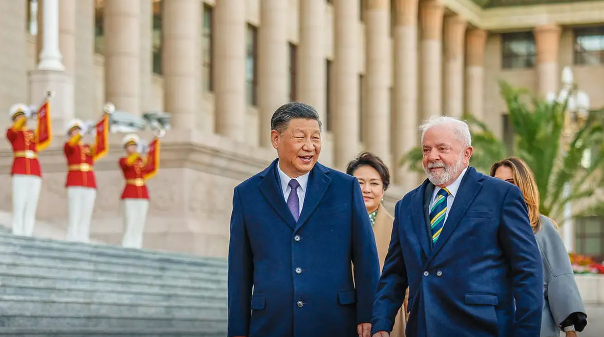 Foto mostrando o presidente Xi Jinping, da China, e o presidente brasileiro, Luiz Inácio Lula da Silva. Os dois aparecem na escadaria de um prédio chinês usando roupas de frio