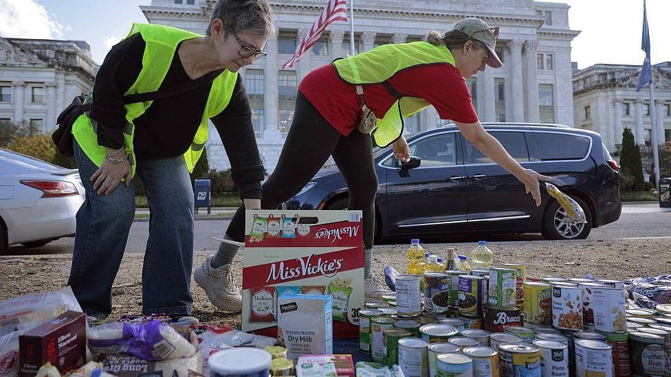 Dos voluntarias inspeccionando latas y paquetes de alimentos donados