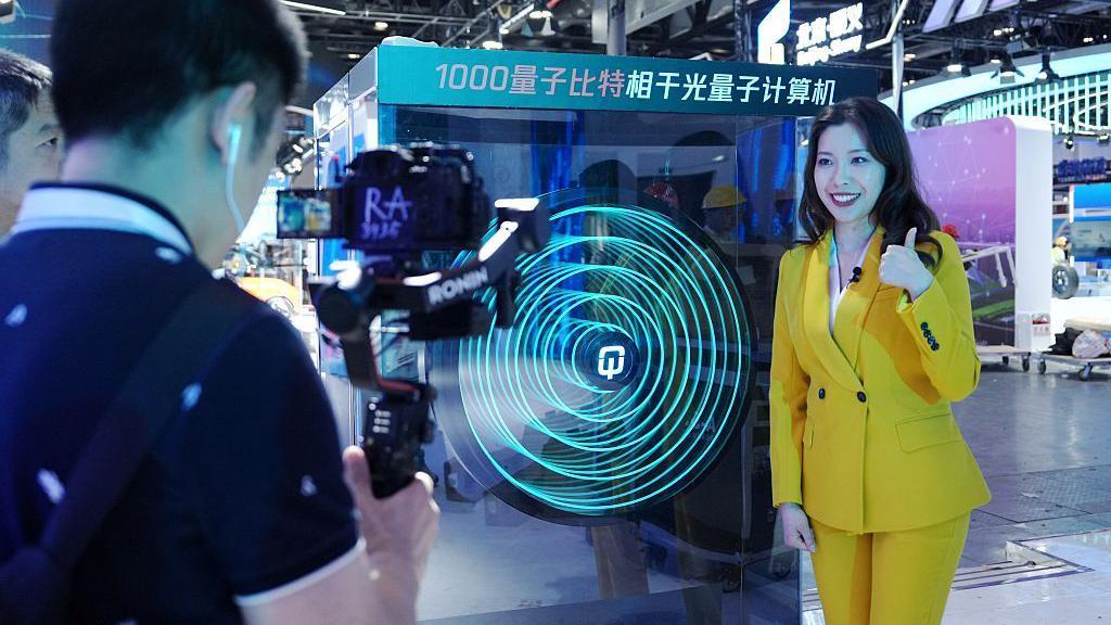 Una reportera junto a una computadora cuántica en 27th China Beijing International High-tech Expo en China National Convention Center